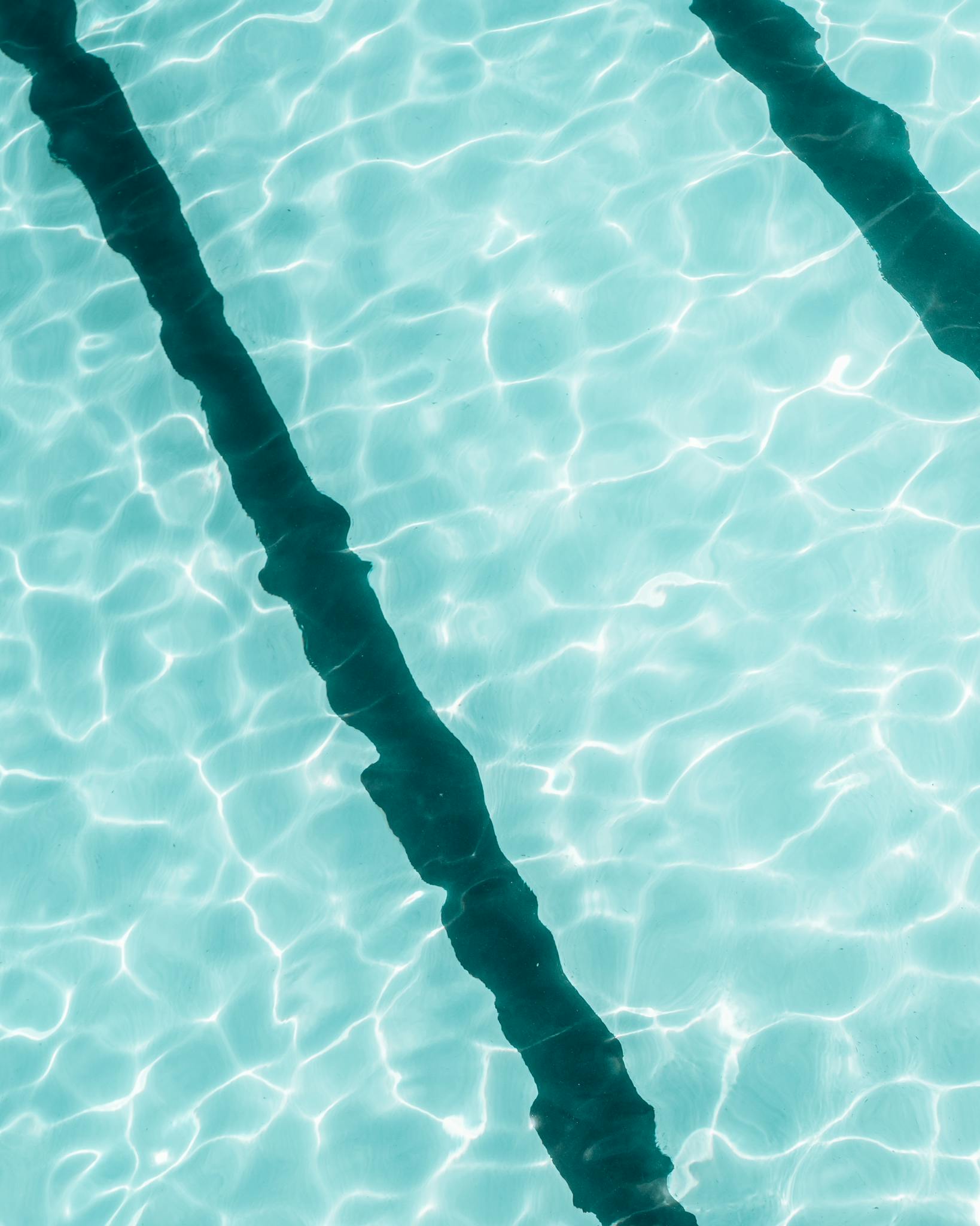 From above outdoor swimming pool with tracks and rippling clean water reflecting bright sunshine